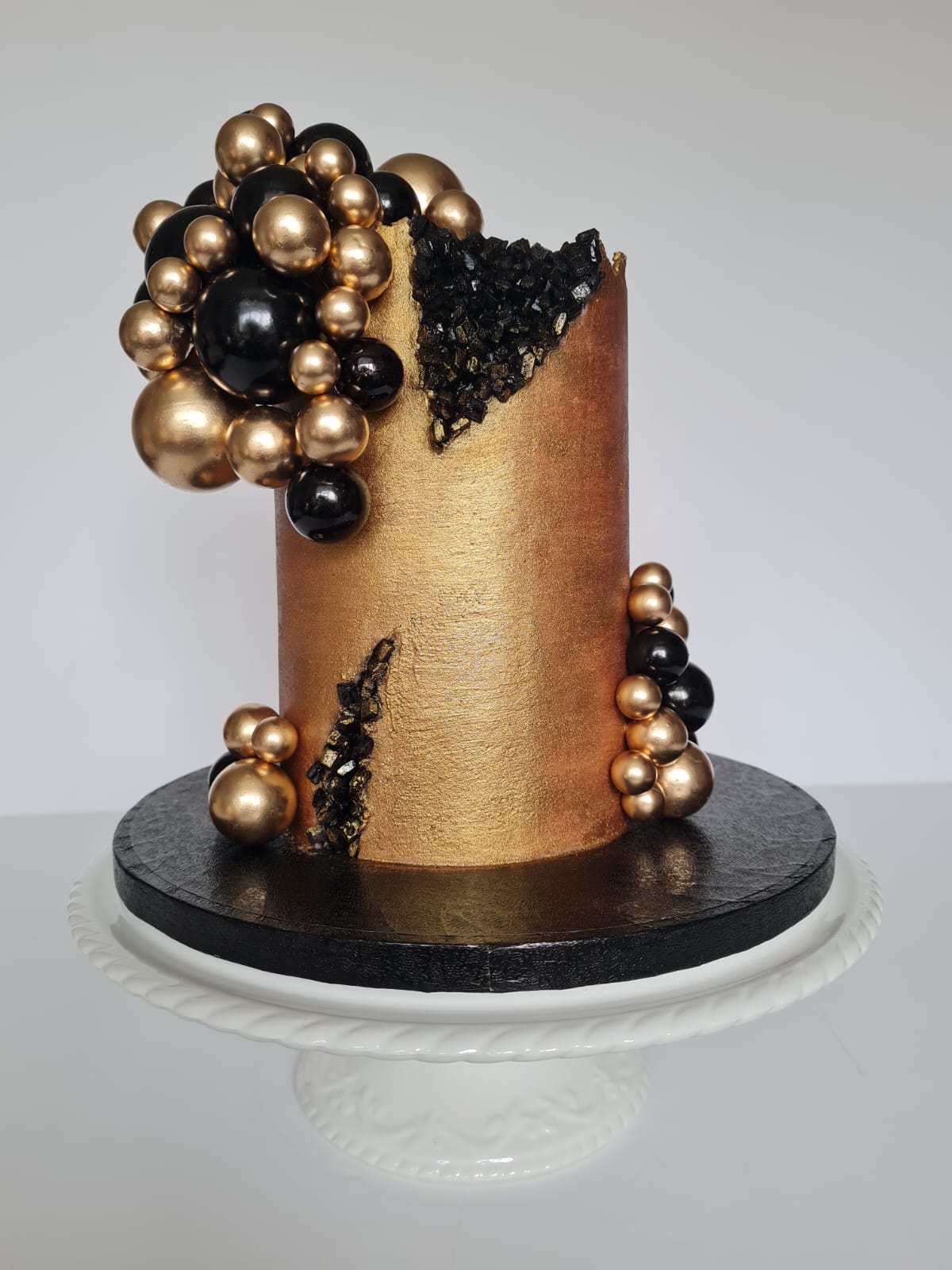 Sugar free birthday cake — gold-dusted chocolate with metallic gold sphere decorations on a glass cake stand