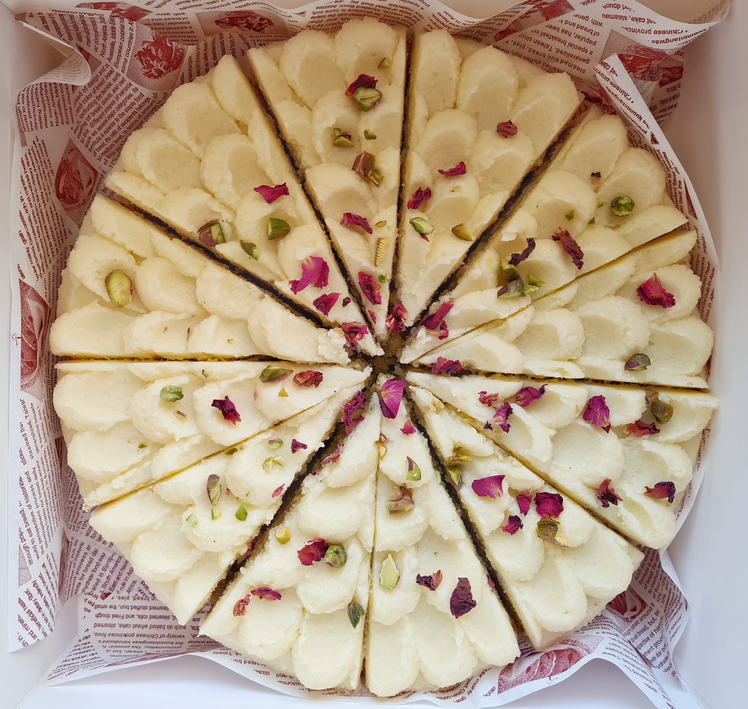 Sugar free carrot cake with piped cream cheese frosting, pistachios and dried rose petals, made with almond flour