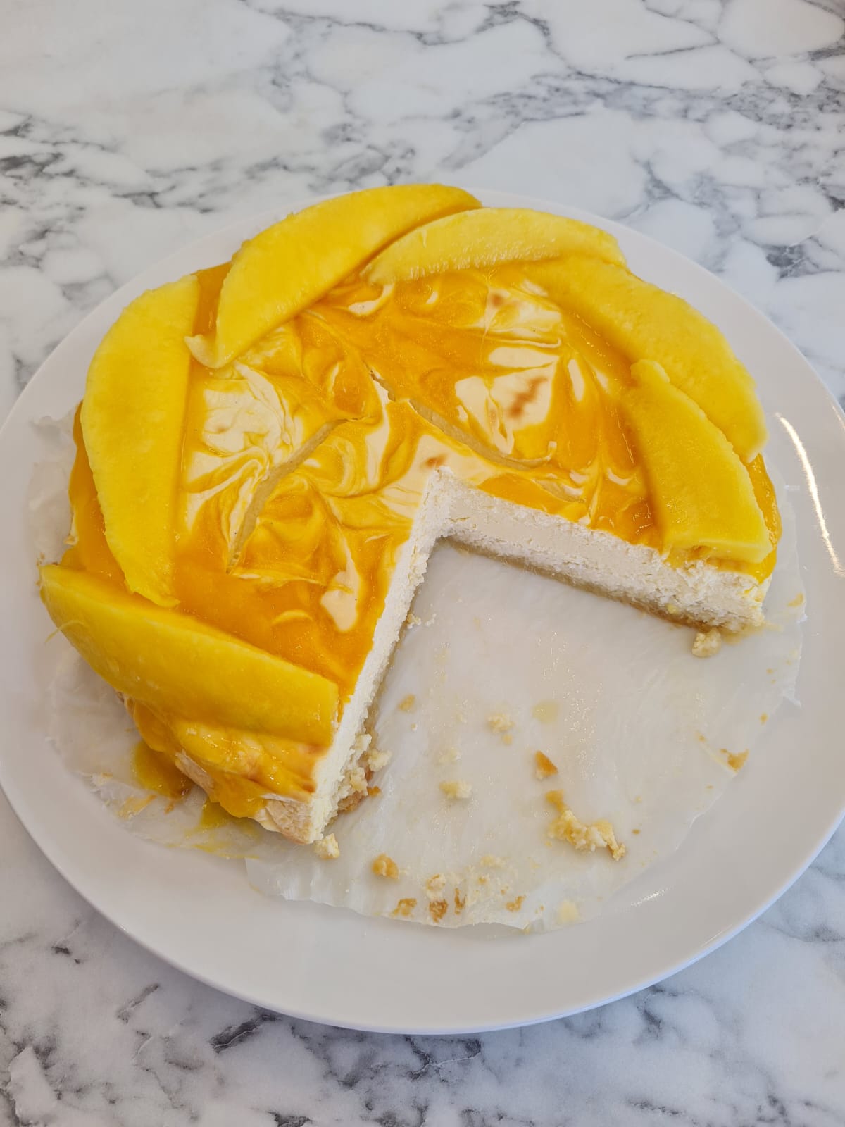 Sugar free mango cheesecake with swirled mango coulis topping and fresh mango slices, sweetened with stevia
